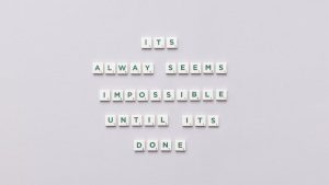 Motivational quote 'It always seems impossible until it's done' in Scrabble tiles.